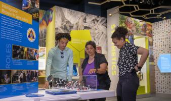 Mother with two teenaged children looking at Museum exhibit. 