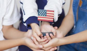 Young people holding a small American flag together.