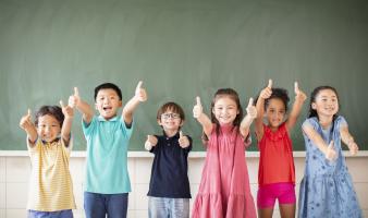 Children with their thumbs up.