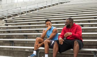 Coach and teen talking on bleachers. 