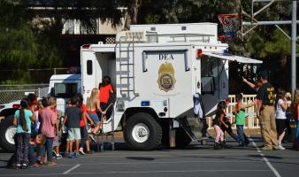 Children meeting DEA special agents and touring the inside of a large white trailer with DEA logo on the side