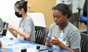 Two students pressing their thumbs in blue silly putty. 