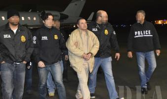 Four law enforcement officers transport a criminal in handcuffs.