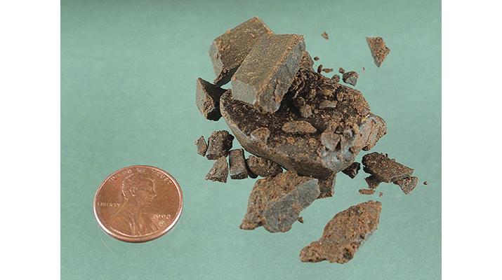 Chunks of hashish next to a penny for scale
