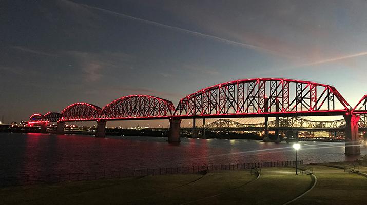 Long bridge with three arches lit up red at night