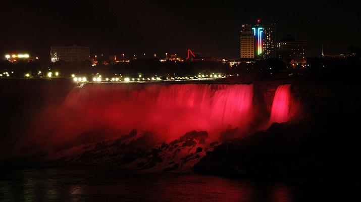 Large waterfall lit up red at night