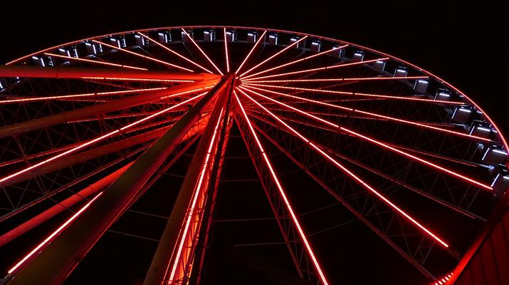 Large Ferris wheel lit up red at night