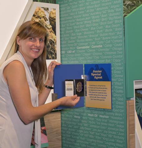 Visitors Services Coordinator Liz holding the Junior Special Agent badge.