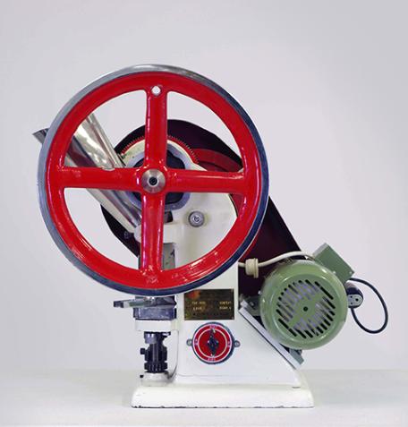 A red, green, and white tablet press.