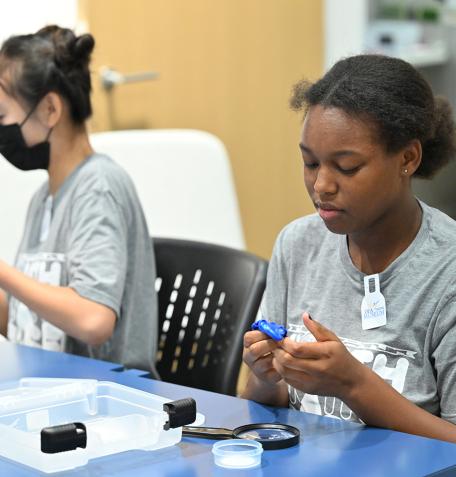 Two students pressing their thumbs in blue silly putty. 