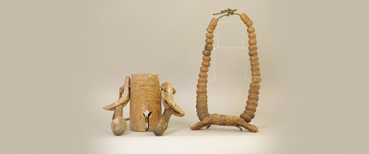   A wooden bell next to a wooded, beaded bridle.
