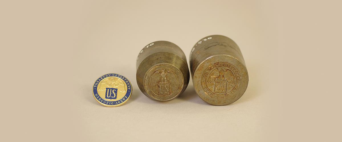 A gold-and-blue badge next to both halves of a steel mold.