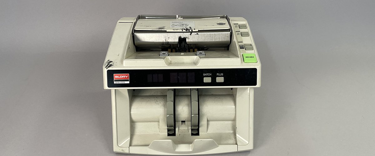   Beige plastic money counter with screen on front
