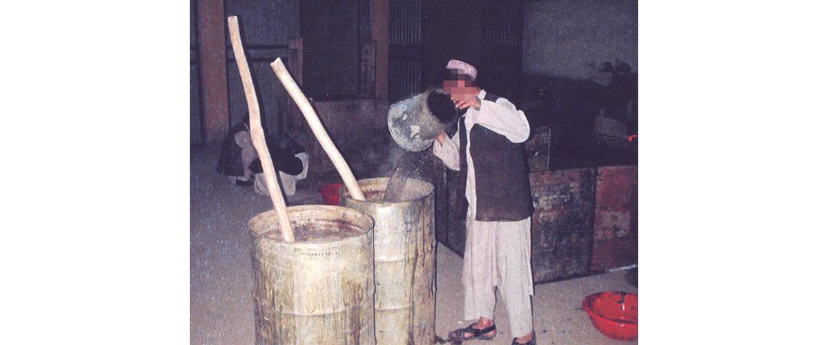 A man adding hot water to a calcium-opium solution in barrels