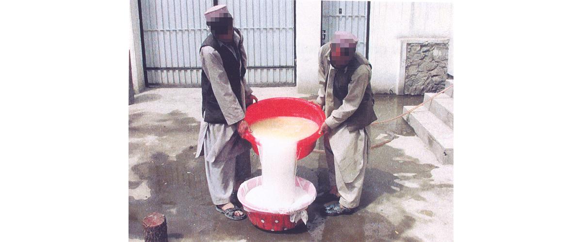 Two men pouring one bucket of solution into another