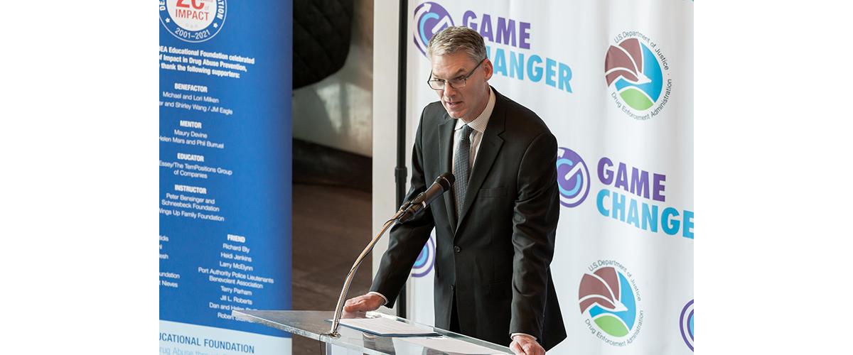 A man delivers a speech at a glass podium.