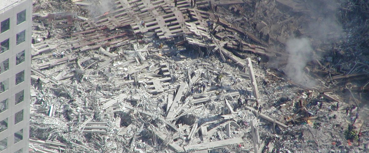 Recovery workers appear as specks against the smoldering rubble of Ground Zero in New York. National Archives.
