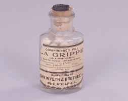 A glass bottle of pills labeled "La Grippe."