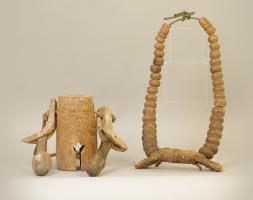 A wooden bell next to a wooded, beaded bridle.